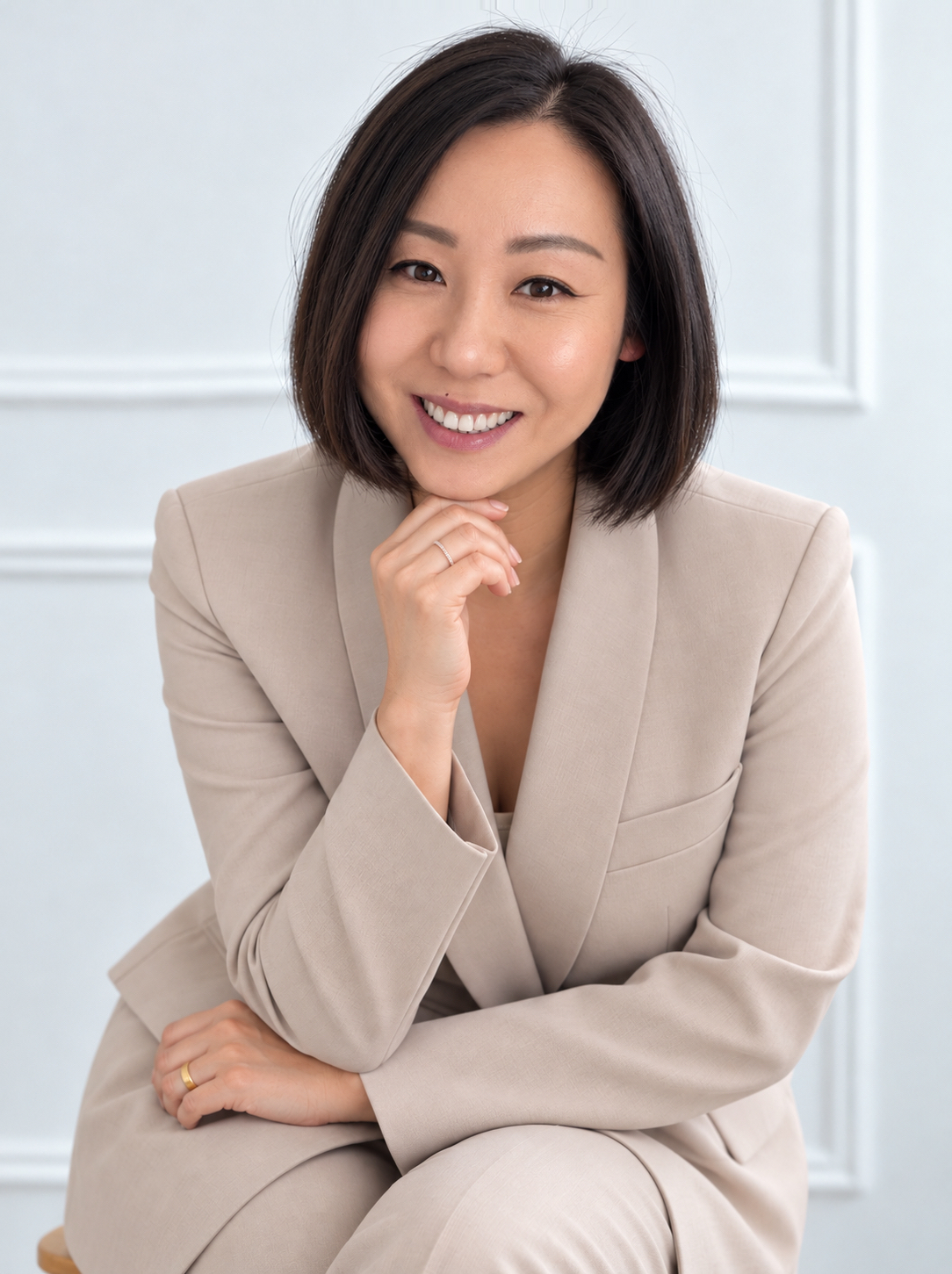 Professional portrait of Angie Lee seated in a beige suit